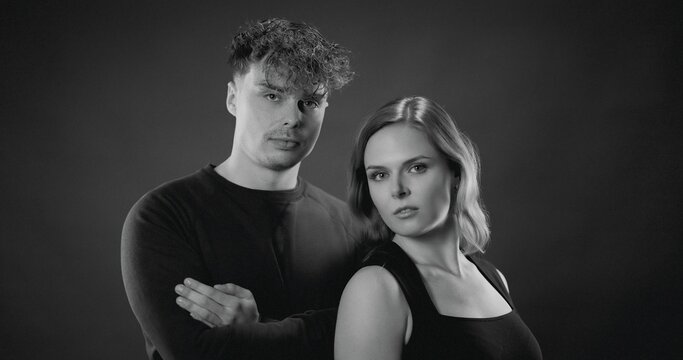 Young man and woman standing together in a black and white studio portrait