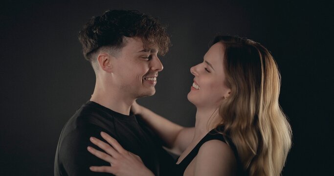 Young couple embracing and smiling, sharing a happy moment in a studio