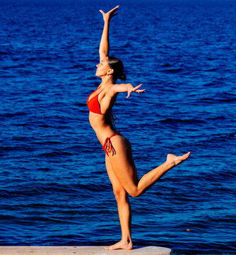 Woman balancing on one leg near lake in washington, USA