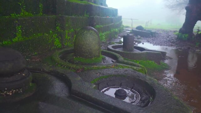 Closeup shot of Shiva Linga besides an old temple at Nageshwar temple at Khireshwar near Malshej Ghat in Maharashtra, India during the monsoon season. A sacred symbol of Lord Shiva in Hinduism.