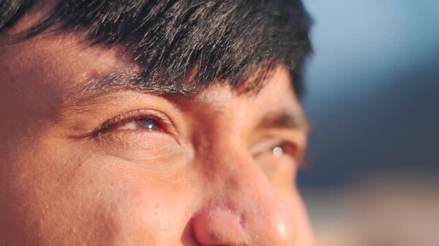 Closeup shot of brown colored eyes of an Indian man squinting while looking at the sky during the evening in Manali, India. Closeup shot of eye signifying hope. Man searching for answers concept. 