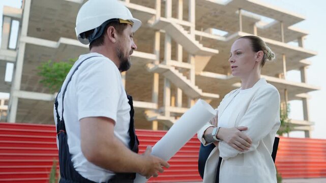 Architect and construction worker discussing building documentation during a tense meeting at a residential construction site. Business negotiation, project management and construction planning 