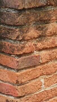 Vertical close-up background of weathered old brick wall texture with warm earthy tones, suitable for rustic, vintage and architectural design use.
