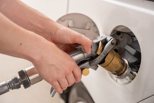 A woman fills a car with gas. Close-up of her hands. 