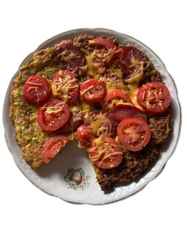 Homemade zucchini frittata with tomatoes, sausage and melted cheese isolated on transparent background, top view meal