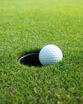 Close-up of golf ball on edge of hole on green