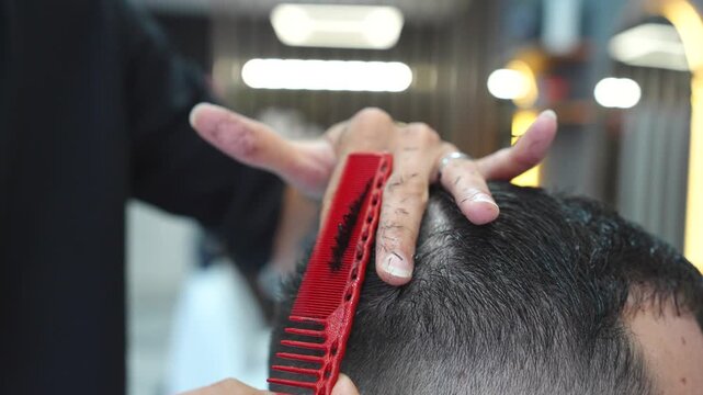 Professional hairstylist using comb and scissors to cut a man's hair in a modern barbershop