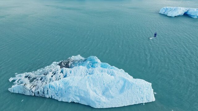 Drone tracks a lone kitesurfer across Lago Argentino near Perito Moreno Glacier, El Calafate, Santa Cruz, Argentina, navigating turquoise glacial water between floating icebergs, drone tracking.