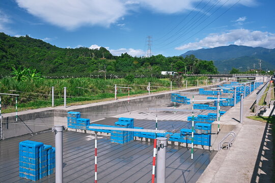 Yilan County, Taiwan - Jul 19, 2026: Aerial view of dry concrete whitewater slalom canoe course with blue obstacle blocks, Sanxing, hills, farmland beyond.
