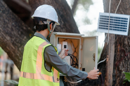 Engineer checks solar cell electrical cabinet wiring outdoors in field