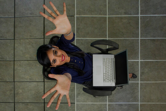 Businesswoman sitting on a chair in office looking up using laptop