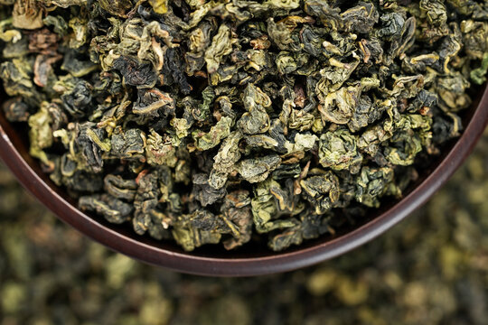 Premium Tieguanyin in dark wooden bowl on green tea pattern background