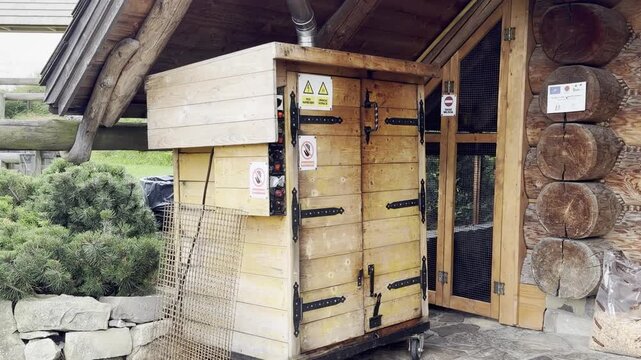 Wooden utility cabinet with open door and warning signs beside a rustic cabin outdoors