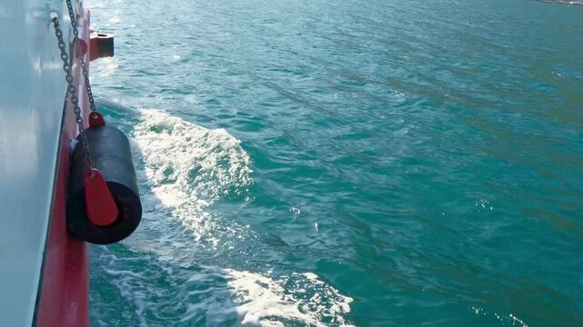 A view of clear blue water with gentle waves created by a boat. The scene captures the tranquility of the sea on a sunny day.