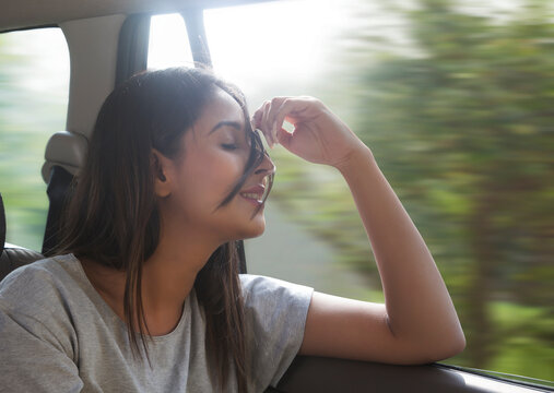 Beautiful young women in car hair gets blown by the wind