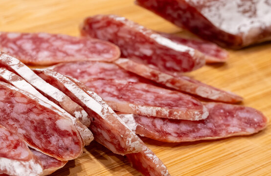 Sliced fuet sausage on wooden board closeup