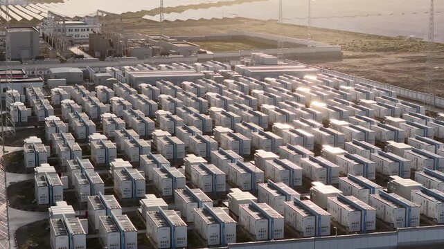 Aerial View of Battery Energy Storage Containers Reflecting Golden Sunlight Near Water in Qinghai, China