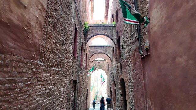 Walking through arched medieval alley in Siena Italy