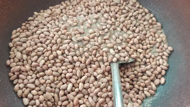 Roasting peanuts with sand in a large pan