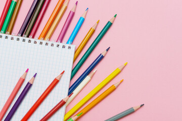 Obraz premium Colored Pencils Fan with Grid Notepad on Pink