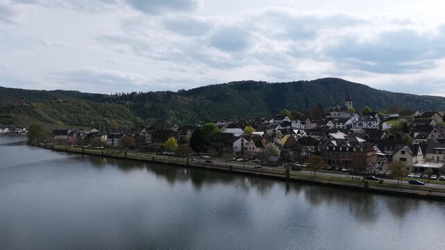 Drone view flying low over calm water of Moselle river and Cochem town in Germany. Aerial, copy space