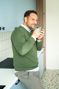 Professional man pausing for a coffee break in a modern office kitchen, enjoying a hot drink while considering his legal or bookkeeping responsibilities