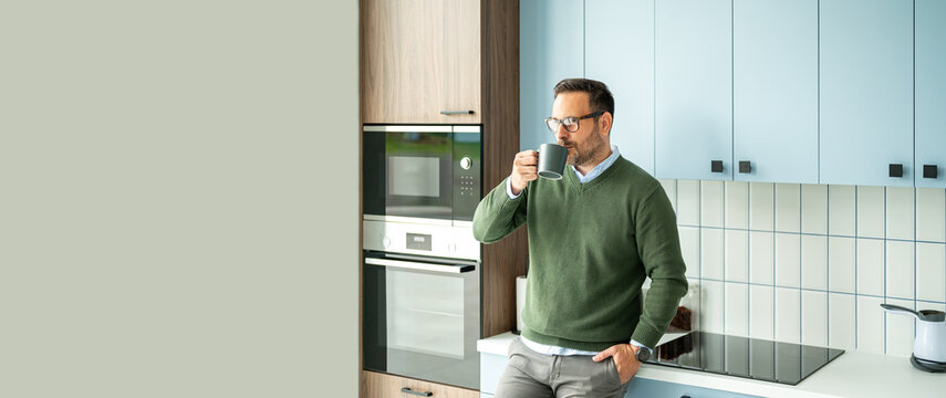 Professional man enjoying a hot drink in a modern kitchen, taking a thoughtful break from remote work activities like legal consultation or accounting tasks