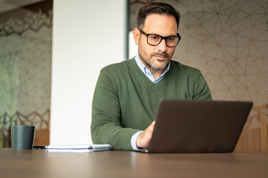 Businessman in modern office working on a laptop, concentrating on tasks, managing data, and focusing on business development and strategic planning