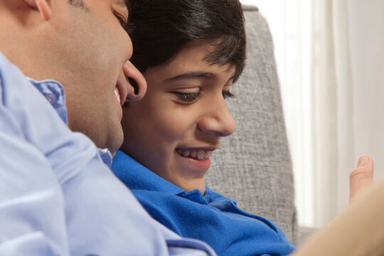 
Close-up of father and son looking at mobile phone