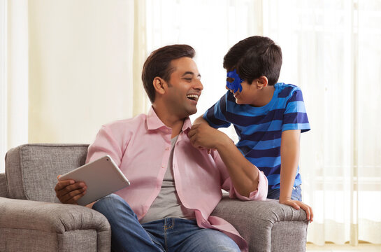 Boy with face mask laughing with his father looking at each other
