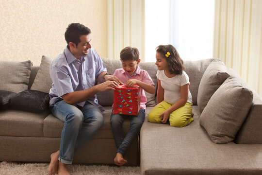 Daughter watching her father and brother opening gift