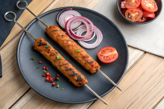 Grilled Seekh Kebabs with Onions, Spicy Meat Skewers on Plate, Indian Style Kebabs with Tomato, Charred Seekh Kebab Platter, Traditional Grilled Meat Skewers