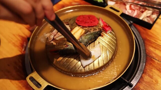 Top view of the traditional asian grill or hot pot in Thail restaurant cooking seafood and meat