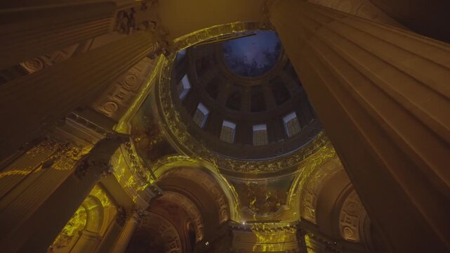 Another angle of a richly gilded church dome interior in Paris, showing ornate columns and coloured windows.
