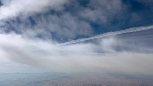immersive pilot&rsquo;s perspective in a flight at supersonic speed through ethereal stratus clouds and jet trails in a blue sky.. 4K uktra-realistic shot.