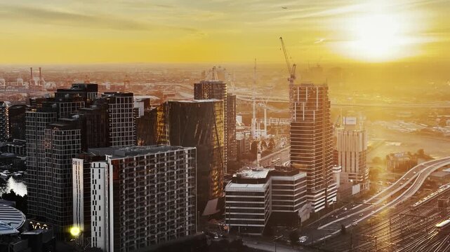 High-angle cityscape modern skyline with moving morning traffic and railway lines, modern skyscraper under construction during a bright Melbourne sunset, Australia