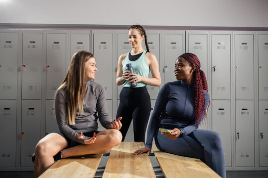 Diverse women friends talking in gym changing room