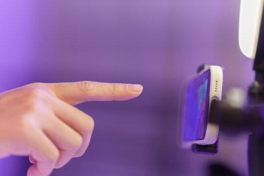 Cropped hand pointing finger to touch screen on mounted smartphone
