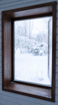 Minimalist dark wooden window frame mockup with open sash looking at soft blurred snowy winter landscape
