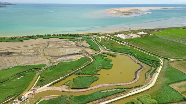 Aerial view of restored coastal wetlands, lagoons and rice fields in Ebro Delta Natural Park, Spain. Drone panorama of Mediterranean shoreline