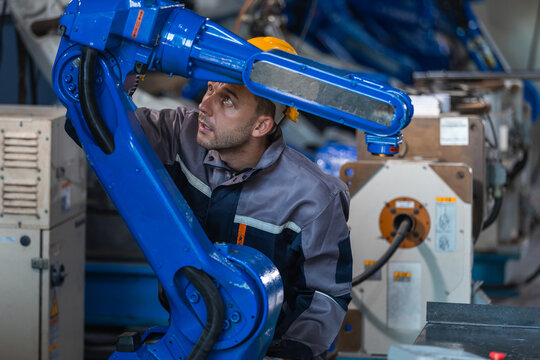 Industrial engineers inspecting and calibrating robotic arm systems in smart factory. automation technology, preventive maintenance, quality control, manufacturing solutions.