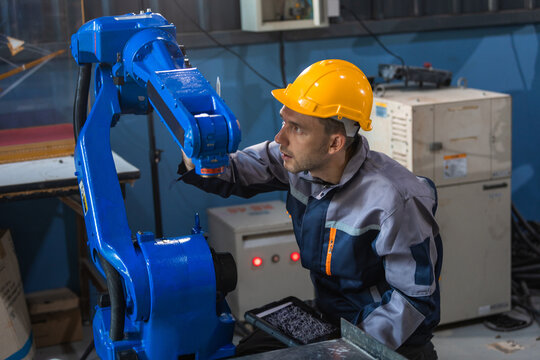 Industrial engineers inspecting and calibrating robotic arm systems in smart factory. automation technology, preventive maintenance, quality control, manufacturing solutions.