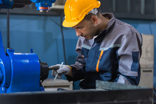 Industrial engineers inspecting and calibrating robotic arm systems in smart factory. automation technology, preventive maintenance, quality control, manufacturing solutions.
