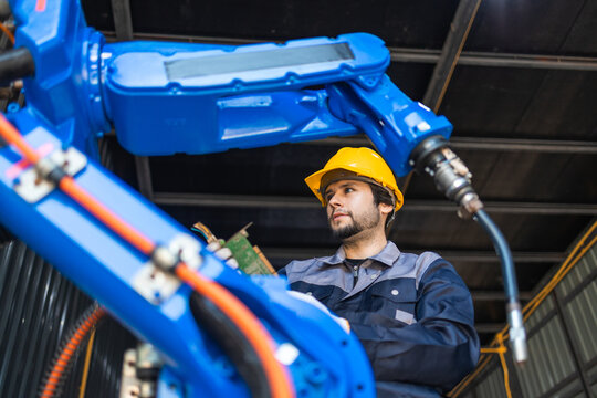 Industrial engineers inspecting and calibrating robotic arm systems in smart factory. automation technology, preventive maintenance, quality control, manufacturing solutions.
