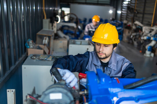 Industrial engineers inspecting and calibrating robotic arm systems in smart factory. automation technology, preventive maintenance, quality control, manufacturing solutions.