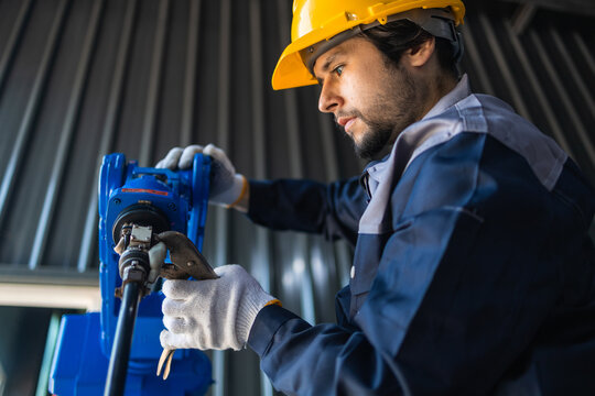 Industrial engineers inspecting and calibrating robotic arm systems in smart factory. automation technology, preventive maintenance, quality control, manufacturing solutions.