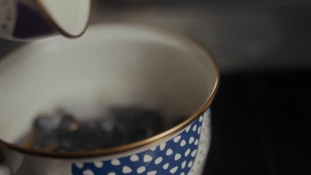 Dark coffee beans fill a patterned ceramic mug with golden rim