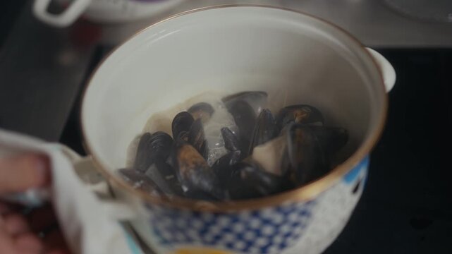 Fresh mussels in a white bowl held by a hand close up