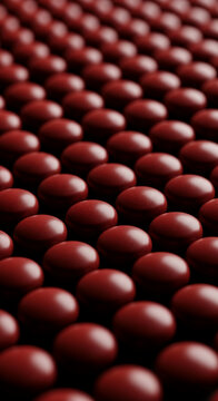 Rows of glossy, dark red pills or capsules arranged in a grid pattern, symbolizing medicine, health, and treatment.