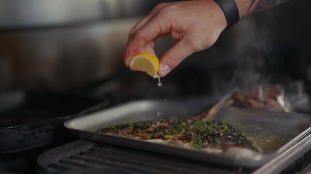 Chef squeezes lemon juice over pan-seared fish on baking sheet